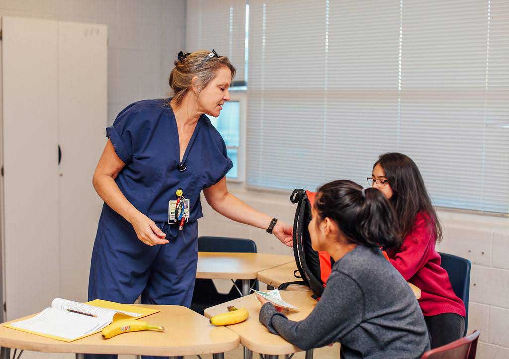 Teacher handing paper to students.