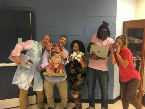 community teachers pose for a photo with props relating to their courses