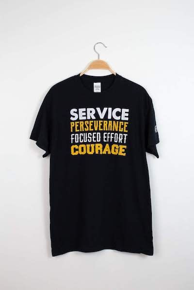 Black t-shirt that reads "service perseverance focused effort courage" in on the road branding material